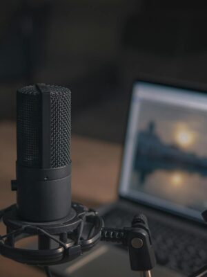 Close-up of a microphone with a pop filter and laptop, ideal for modern studio production.