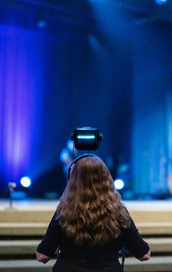 Female camera operator records live concert, capturing vibrant stage performance.