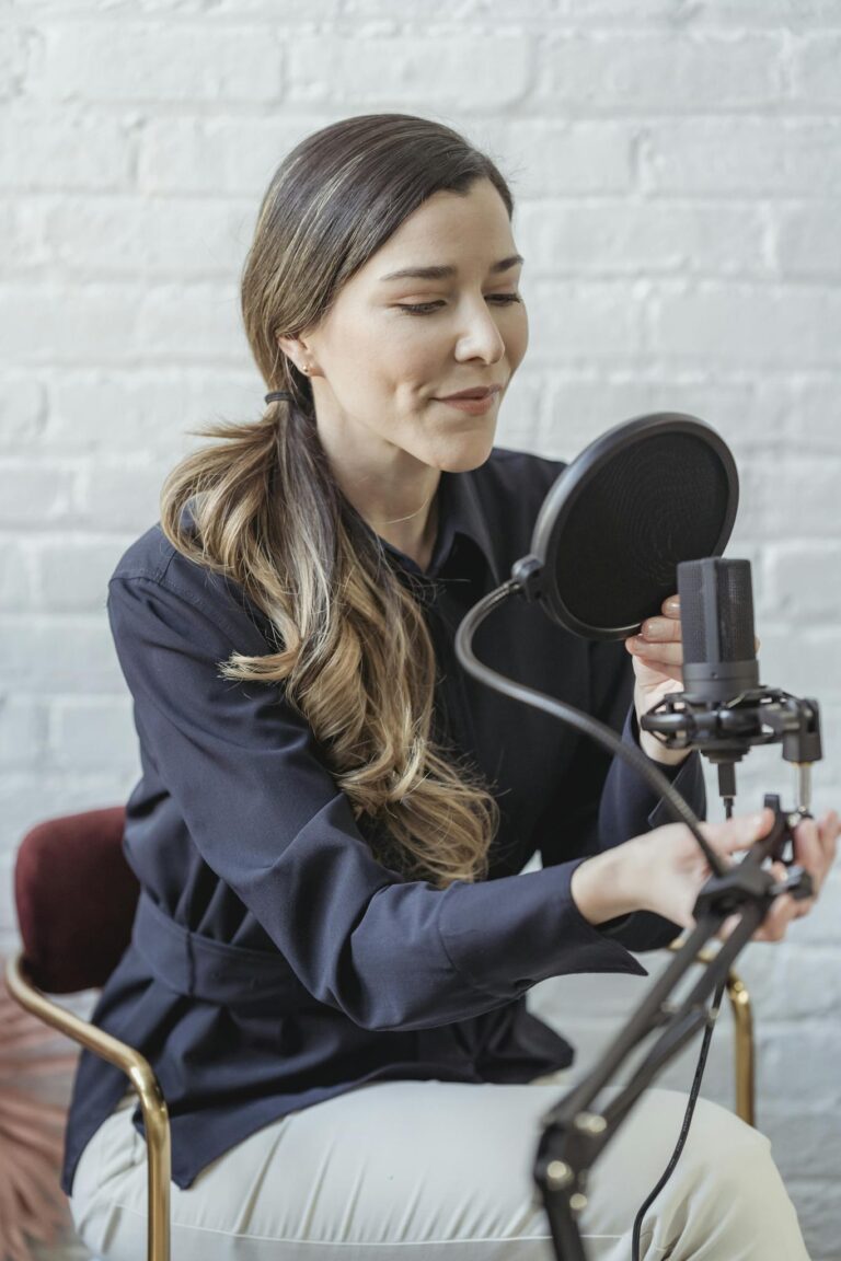 Woman recording a podcast in a modern studio with a microphone and pop filter, showcasing a professional setup.